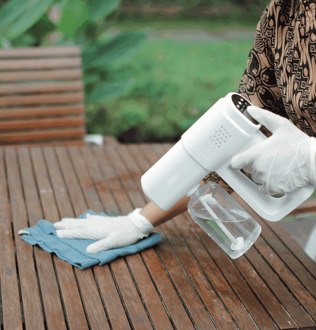 Person disinfecting table with gloves on